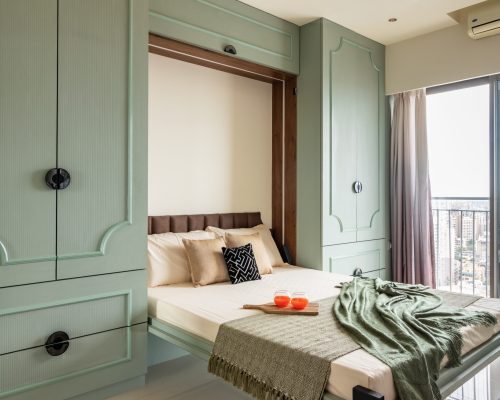 Modern bedroom with a foldable bed integrated into a pastel green wardrobe